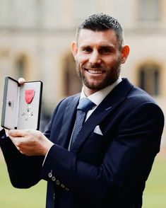 a man in a suit and tie holding up an iphone case with hearts on it