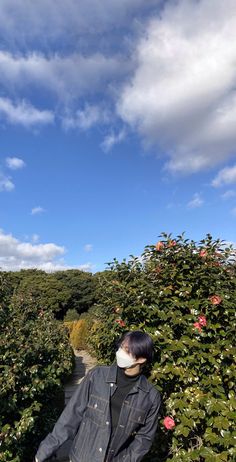 a man walking down a path between bushes and flowers