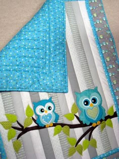 two owls sitting on a tree branch with blue and gray fabric