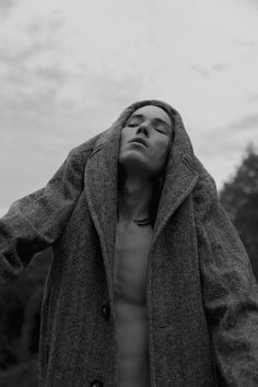 a shirtless man with his hands on his head is standing in front of trees