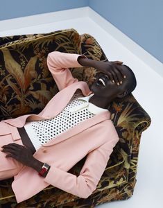 a mannequin wearing a pink jacket and black pants sitting on a floral chair