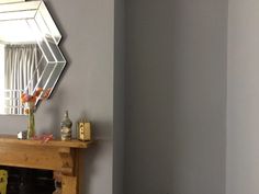 a living room with a fire place and mirror on the fireplace mantel, in front of a gray wall