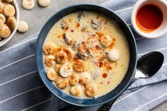 a bowl filled with soup next to two bowls of crackers and sauce on a table