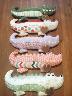 five alligators are lined up on a wooden floor and one is wearing a heart