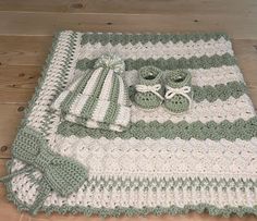 a crocheted blanket and pair of baby shoes on top of a wooden floor