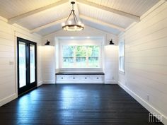 an empty room with white walls and wood flooring on the side, along with black doors