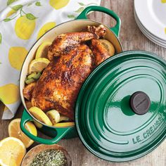 a chicken in a pot with lemons and seasoning next to it on a table