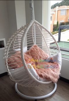 a hammock chair hanging from the ceiling in front of a window with a pink rug on it