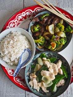 a plate with rice, meat and veggies next to some chopsticks