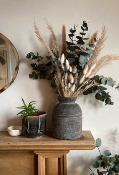 some plants are sitting on a table next to a potted plant and a mirror