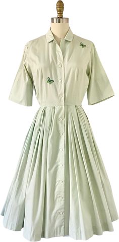 1950s fit-and-flare shirt-dress. Mint green with two green embroidered butterflies on the front. Features pleats at the waist of the skirt. Buttons up at the front.Label is Sue Brett ('A Sue Brett Junior Dress'). No fabric information, but it seems like a cotton. A slight "worn" look in some areas, but in over-all very good-excellent vintage condition!No size on tag. Fit size XS-S best.Measurements (laid flat and doubled)Bust: up to 38"Waist: 22"Hips: Open sizeLength: 41" Classic Green Spring Dress, Classic Green Cotton Dress, Spring Dress With Butterfly Embroidery And Short Sleeves, Spring Dresses With Butterfly Embroidery And Short Sleeves, Classic Green Dress With Button Closure, Green Collared Cotton Dress, Green Cotton Collared Dress, Junior Dress, Embroidered Butterflies