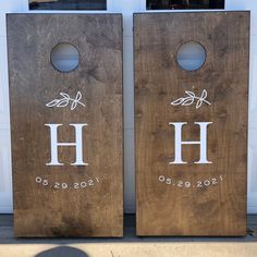 two cornhole boards with the letters h and h painted on them, sitting in front of a garage door