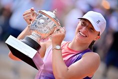 a woman holding up a trophy in front of her face and wearing a pink shirt