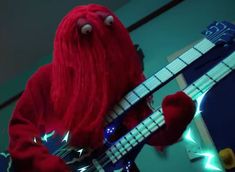 a red stuffed animal playing a bass guitar