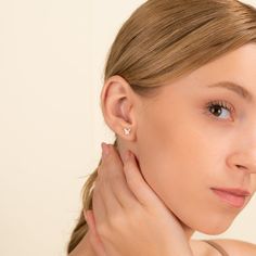 a woman with her hand on her neck looking at the camera and touching her ear