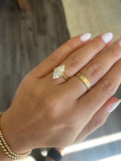 a woman's hand with two gold rings on top of her fingers, and a diamond ring in the middle