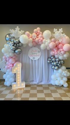 a table with balloons on it and a number one sign in front of the balloon arch