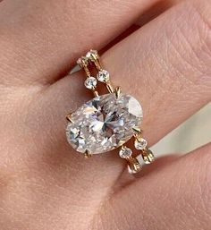 a woman's hand with a ring on it that has an oval shaped diamond in the center