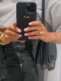 a woman is holding her cell phone in her right hand and wearing rings on her left wrist