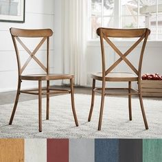 two wooden chairs sitting next to each other on a rug in front of a window