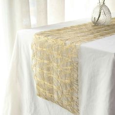 a white table topped with a vase filled with flowers next to a window covered in sheer curtains