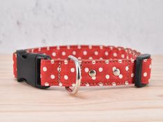 a red and white polka dot dog collar on a wooden table with a metal ring