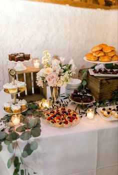 a table filled with desserts and pastries on top of a white table cloth