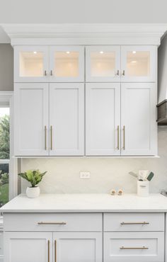 a kitchen with white cabinets and gold pulls on the doors, counter tops and drawers