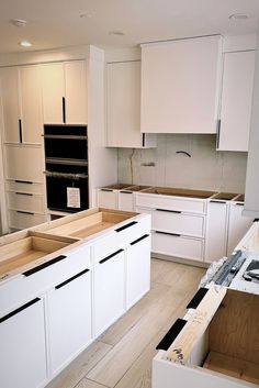 an empty kitchen with white cabinets and black appliances in the middle of the flooring