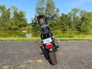 the motorcycle is parked on the side of the road in front of some grass and trees