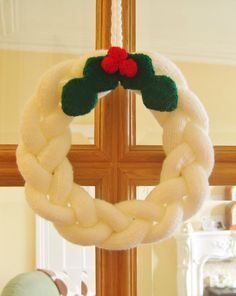 a white wreath hanging from a cross on top of a window sill next to a stuffed animal