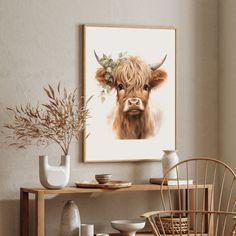 a painting of a brown cow with horns on it's head is hanging above a dining room table