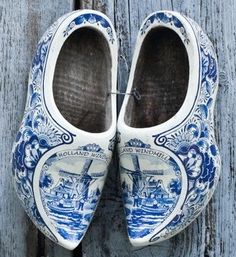 pair of blue and white painted shoes hanging on wooden planks with water in the background