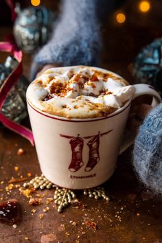 a cup of hot chocolate with marshmallows and cinnamon on the table next to it