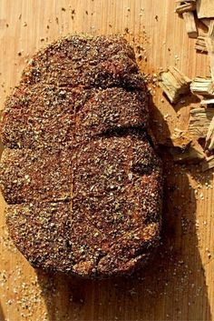 a piece of meat sitting on top of a wooden cutting board next to chopped wood