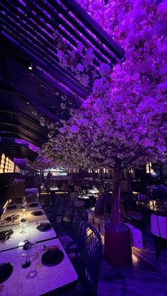 the dining room is lit up with purple lighting and flowers on the trees in bloom