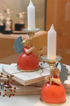 an orange candle holder with angel figurines sitting on top of it next to a book