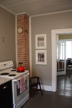 a white stove top oven sitting inside of a kitchen next to a brick wall with pictures on it