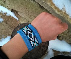 Loom Beaded Cuff Bracelet with Native American Style pattern in blue, white, turquoise, black and beige colors designed by me. The beaded part of the bracelet is sewn on a double-layered blue-jeans-material. Made out of Czech seed beads, 100% cotton jeans material and a metal button clasp.    This bracelet measures 18 cm or 7 inches and is 4,5 cm or 1,77 inches wide.  Color and size can be changed up to order! When ordering, please write me a short message about your wrist circumference. Please Blue Beaded Bracelets For Festival, Blue Wrap Bracelet With Colorful Beads For Festivals, Festival Wrap Bracelet With Colorful Beads, Festival Blue Wrap Bracelet With Colorful Beads, Adjustable Blue Cuff Bracelet For Festivals, Bohemian Blue Cuff Bracelet With Colorful Beads, Blue Beaded Friendship Bracelets For Festival, Blue Beaded Cuff Bangle Bracelet, Blue Beaded Bangle Cuff Bracelet