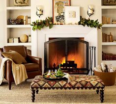 a living room filled with furniture and a fire burning in the fireplace behind a chair