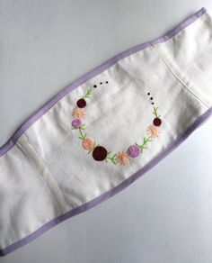 an embroidered piece of cloth with flowers and leaves on the edge, sitting on a table