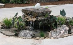 a water fountain surrounded by rocks and plants