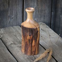 a small wooden vase sitting on top of a wooden table next to a string and twine