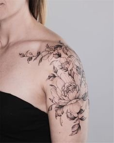 a woman with a flower tattoo on her arm and shoulder is looking at the camera