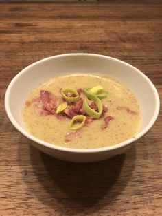 a white bowl filled with soup and toppings on top of a wooden table,