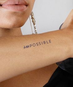 a woman's arm with the word impossible written on it