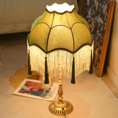 a lamp that is sitting on a table next to a magazine and some pictures in the background