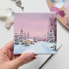 a person holding up a small card with a snowy scene on the front and side