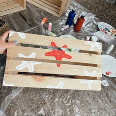 a person is holding a wooden crate with an airplane painted on it and other items scattered around