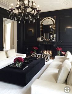 a living room with black walls and white couches in front of a fire place